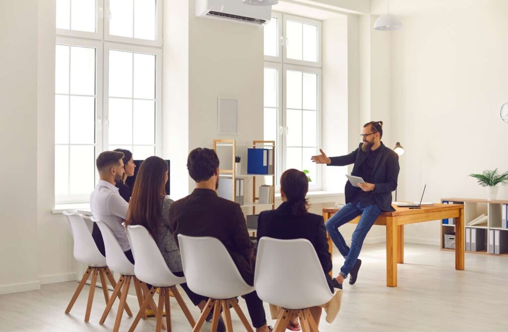 Un hombre está dando una charla a un público atento, que escucha y toma notas.