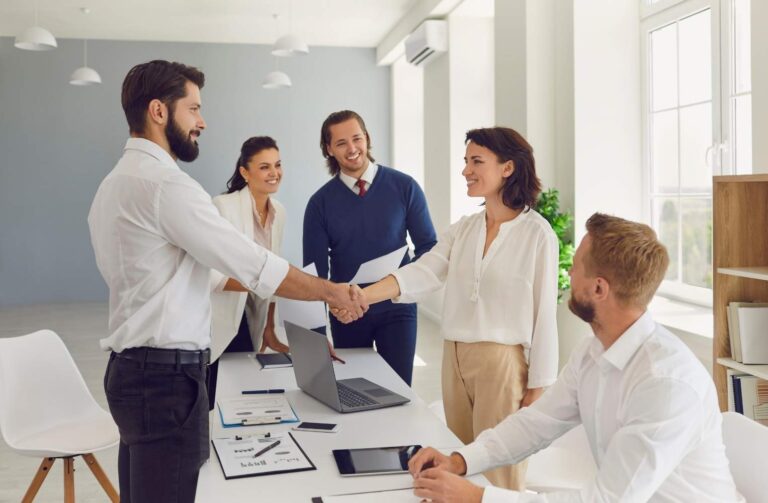 Personas de negocios estrechando manos en una oficina moderna.