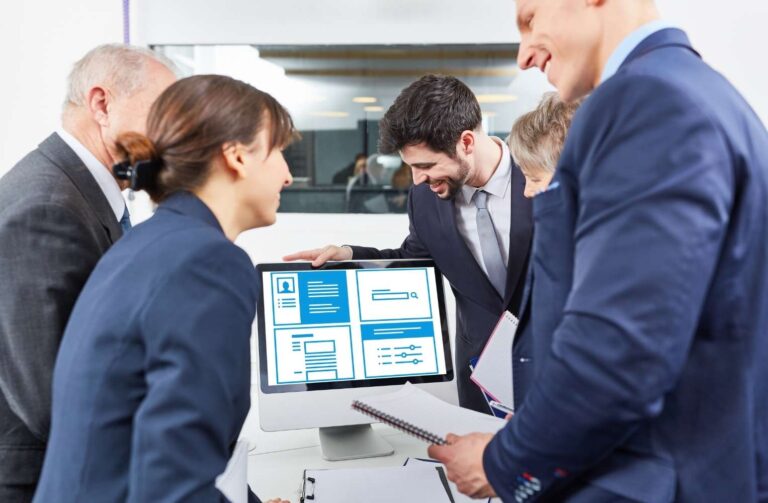 Personas de negocios observando una pantalla de computadora en una reunión.