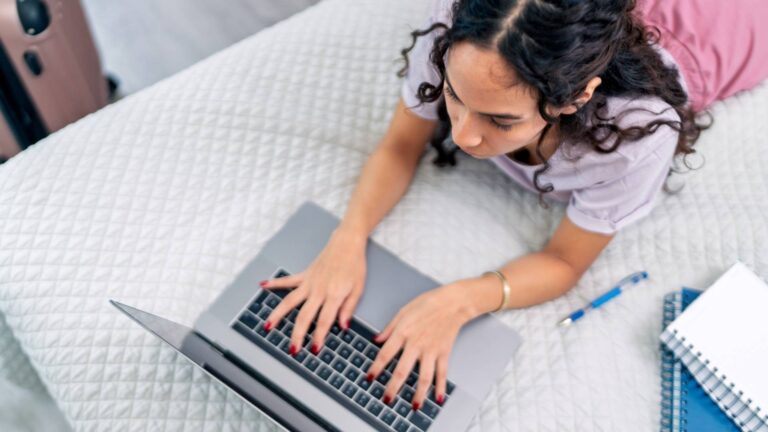 Mujer en su cama con una laptop, sumergida en su trabajo o entretenimiento, en un espacio cómodo y personal