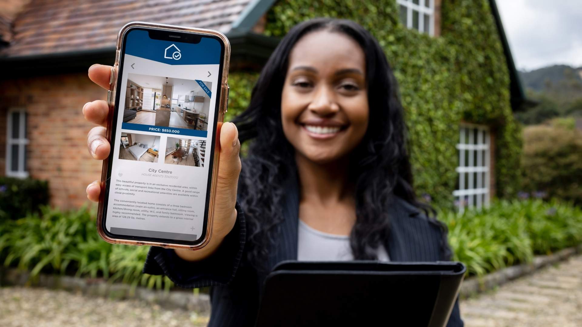 Mujer sosteniendo un smartphone que muestra un sitio web de bienes raíces, destacando las plataformas más usadas
