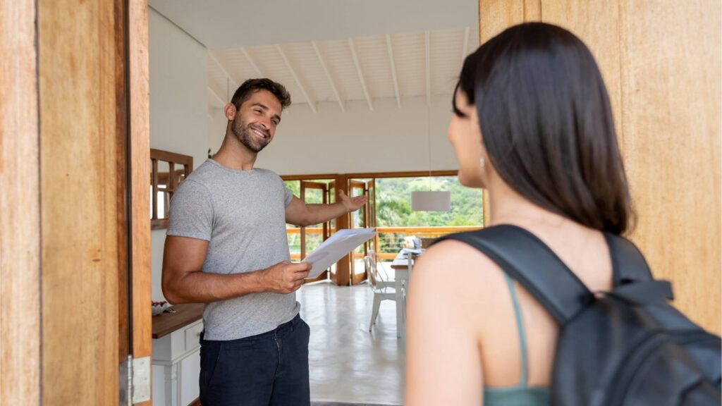 Un hombre y una mujer sonrientes de pie frente a una puerta, listos para ofrecer servicios