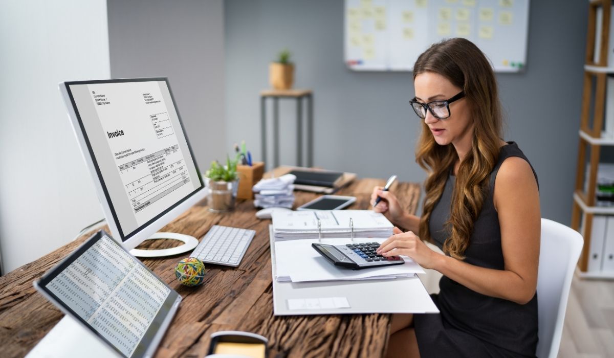 Mujer con gafas trabajando en una computadora sobre deducciones y beneficios fiscales