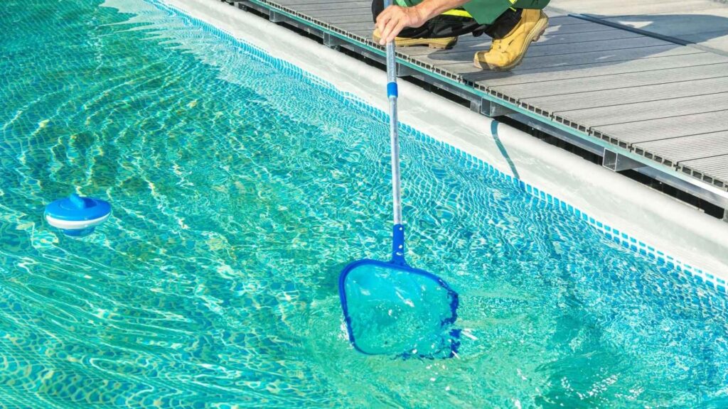 Una piscina con una red, realizando mantenimiento preventivo para casas vacacionales.
