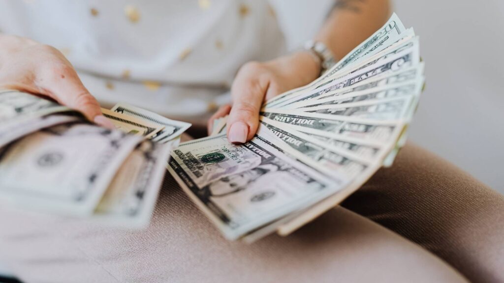 Persona sosteniendo un fajo de billetes en dólares