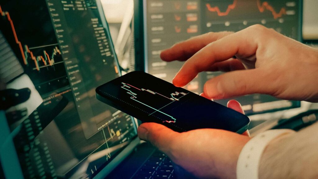 Persona revisando un gráfico del mercado de valores en su smartphone, con el título "Precios dinámicos".