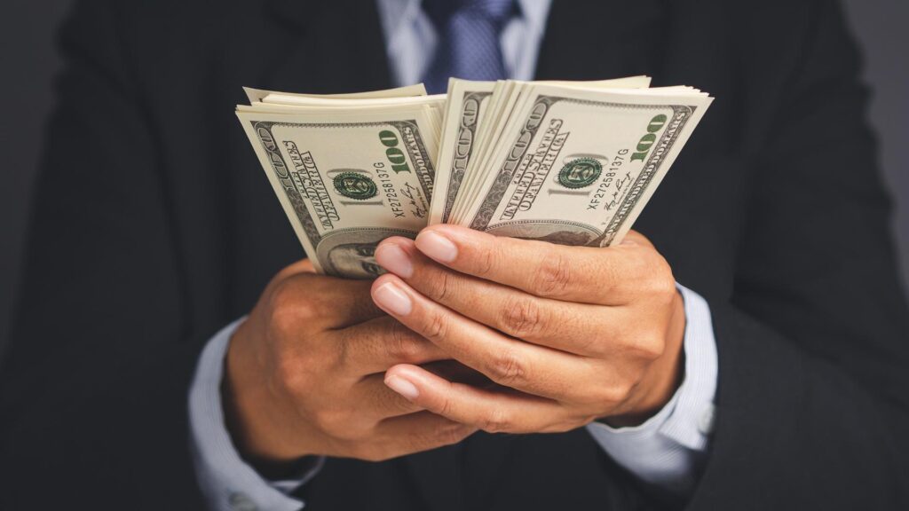 Empresario sosteniendo dinero en las manos, simbolizando oportunidades en el sector de rentas vacacionales.