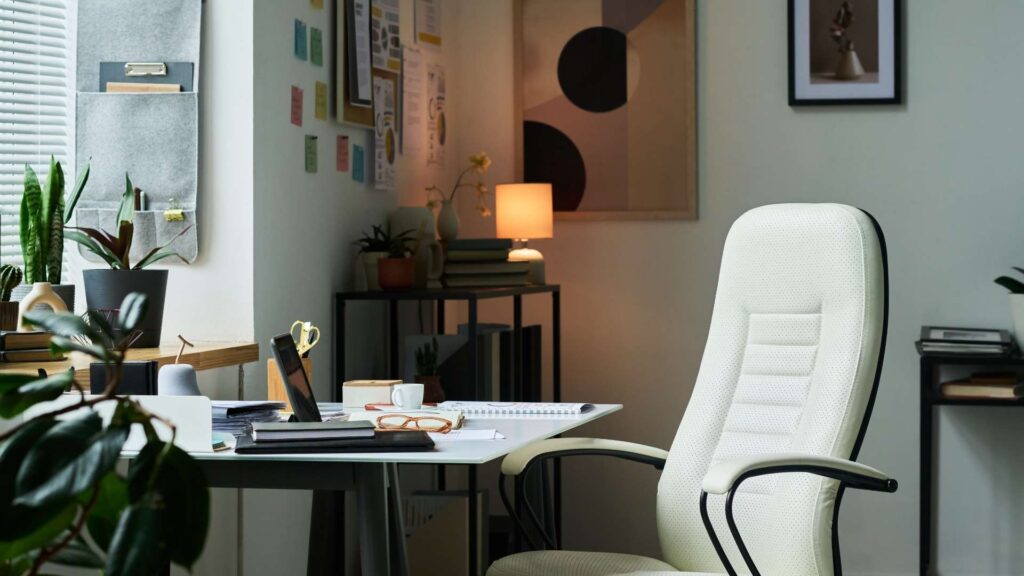 Una silla de oficina blanca se encuentra frente a un escritorio en un entorno de trabajo para nómadas digitales.