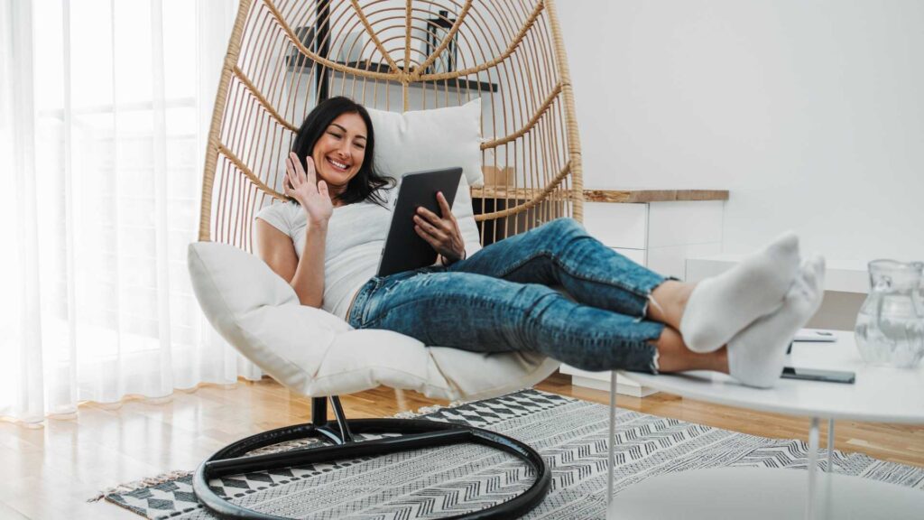 Mujer sentada en una silla, usando una tableta, representando a los nómadas digitales en un entorno de trabajo.