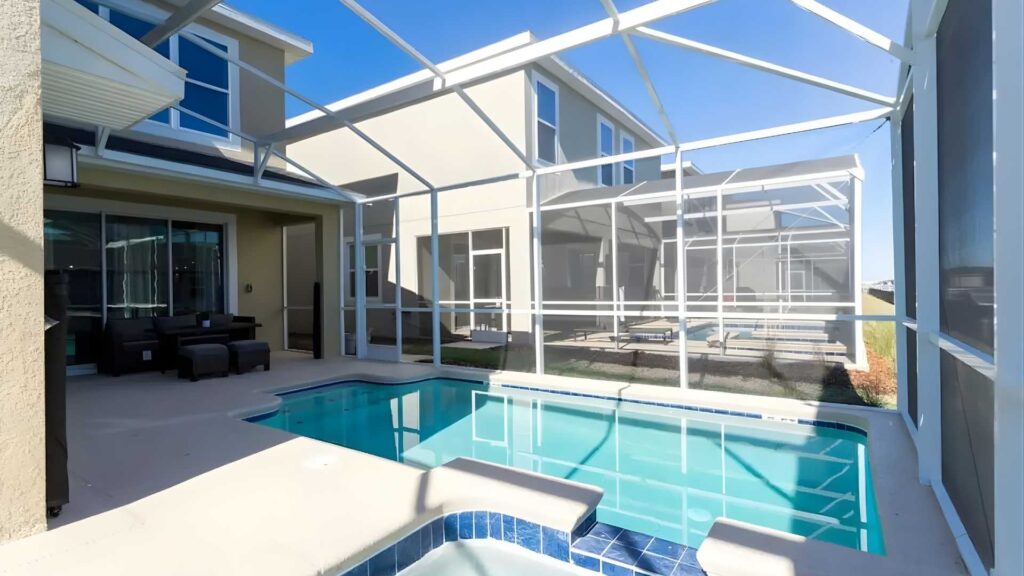 Una piscina en un hogar con un porche de vidrio decorado, creando un ambiente elegante y acogedor.