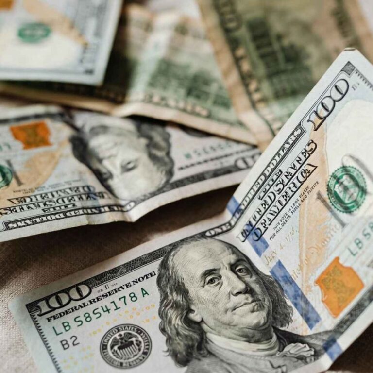 Un montón de billetes de cien dólares apilados sobre una mesa, representando un caso de éxito financiero.