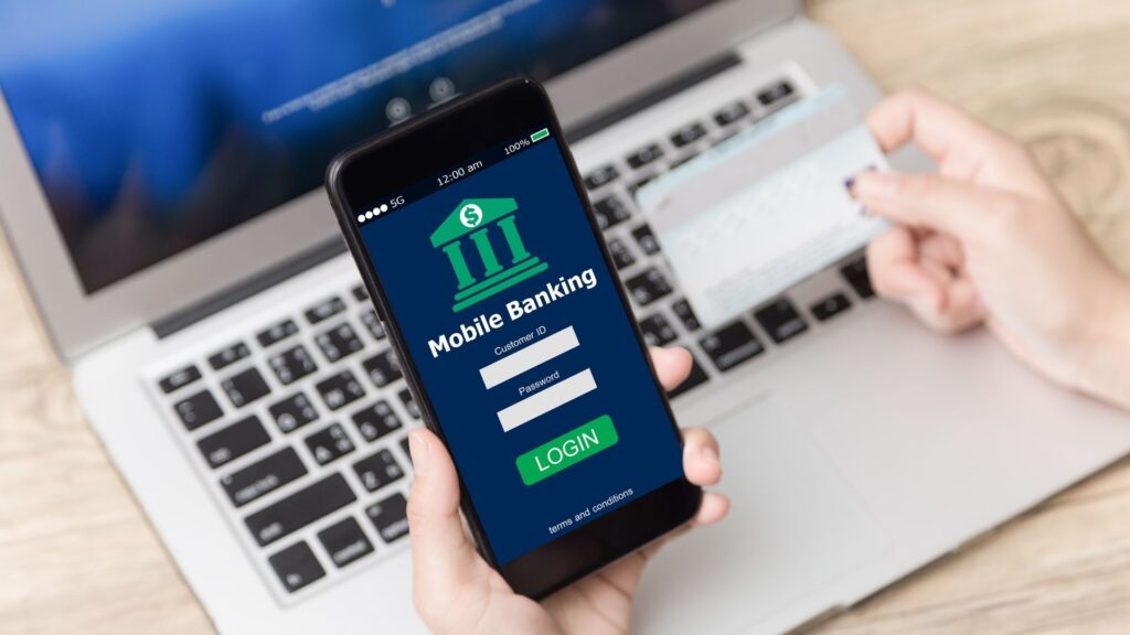 Mano sosteniendo un teléfono inteligente con una aplicación de banca móvil abierta para monitorear los ingresos de una propiedad de inversión.