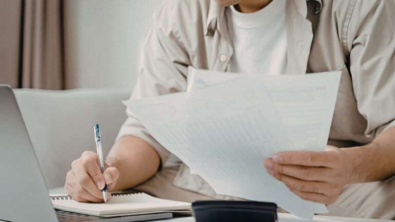 Persona revisando contratos y documentos financieros para la gestión de inversiones inmobiliarias mediante una sociedad de responsabilidad limitada.