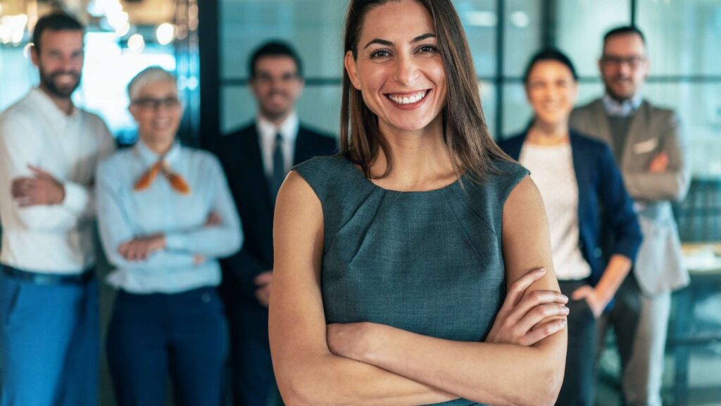 Mujer profesional sonriendo al frente de su equipo corporativo, expertos en inversión inmobiliaria en Orlando 2026.