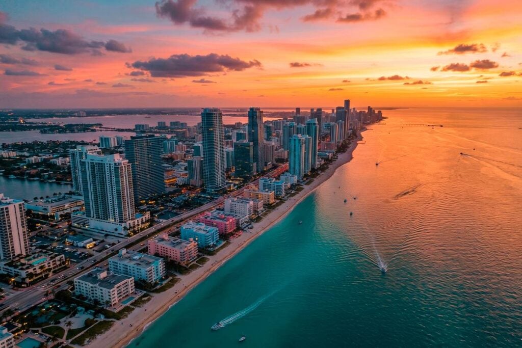 Panorama urbano de Miami frente al mar, destacando el mercado de inversión inmobiliaria de lujo al atardecer.
