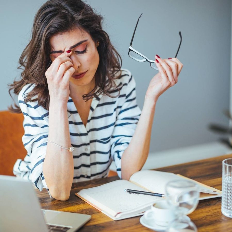 Mujer sentada en un escritorio con los ojos cerrados, reflexionando sobre autogestión o gestión profesional.
