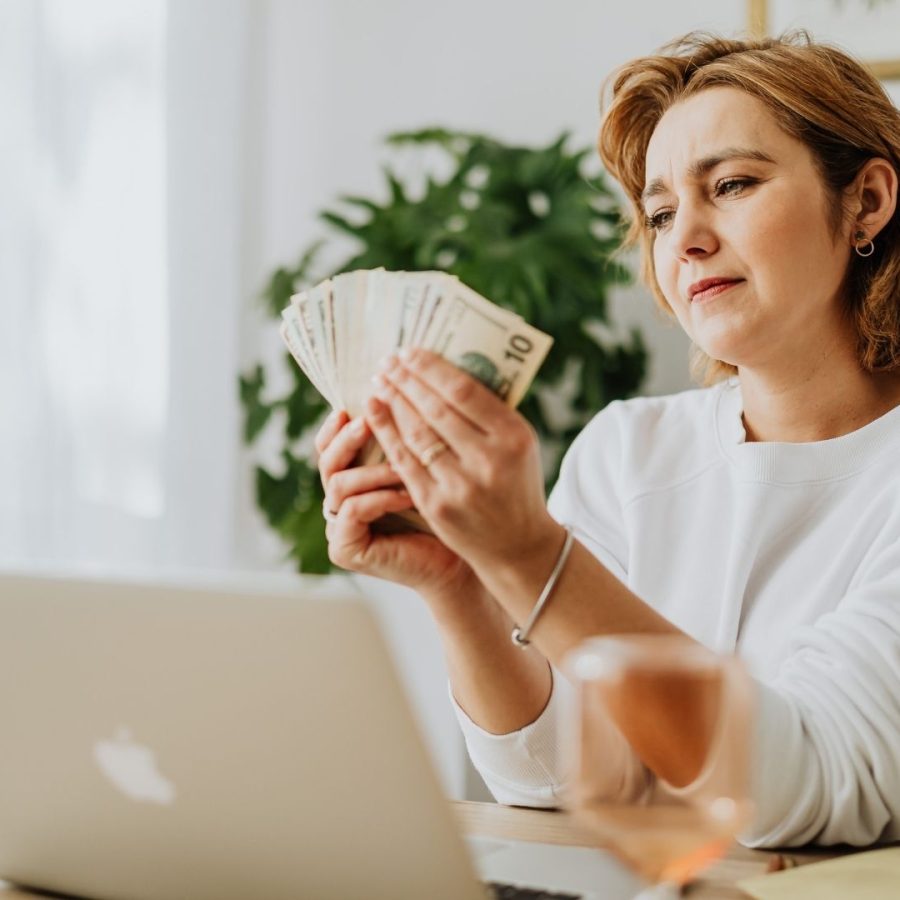 Mujer sentada en un escritorio sosteniendo dinero, en el contexto de una casa vacacional.