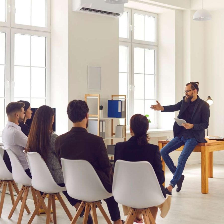 Un hombre está dando una charla a un público atento, que escucha y toma notas.