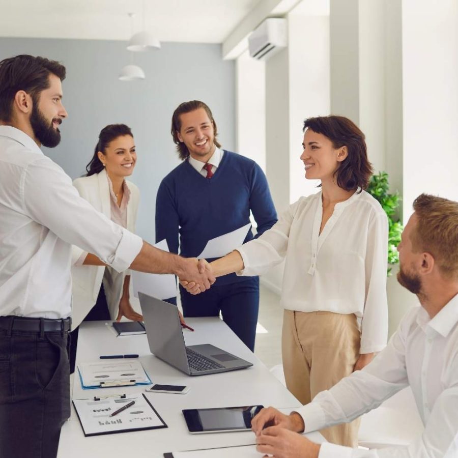 Personas de negocios estrechando manos en una oficina moderna.
