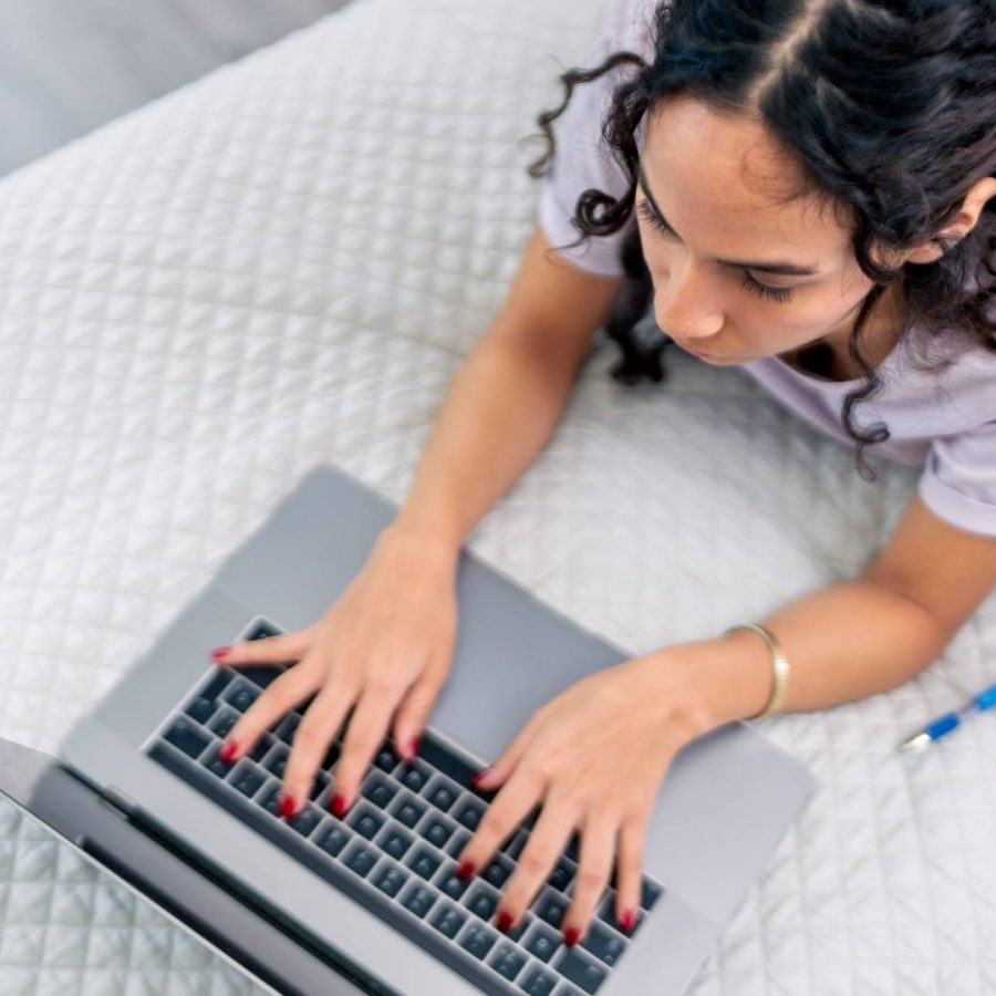 Mujer en su cama con una laptop, sumergida en su trabajo o entretenimiento, en un espacio cómodo y personal