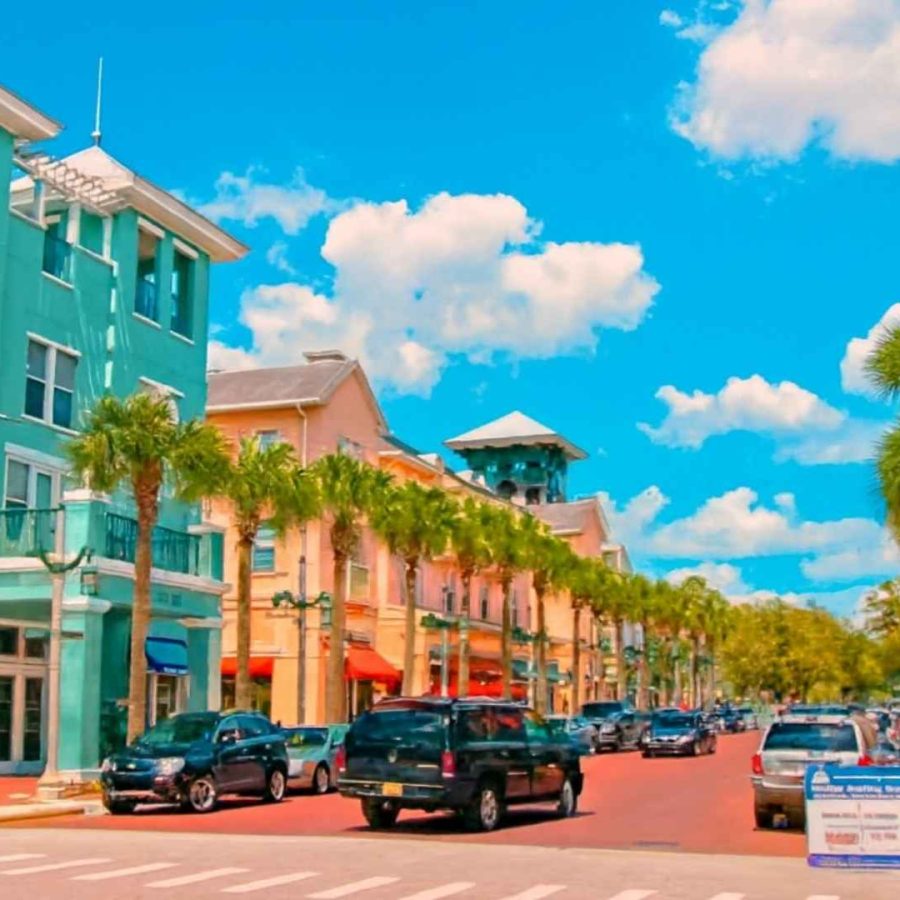 Calle colorida con palmeras y coches, representando un vecindario familiar en Orlando.