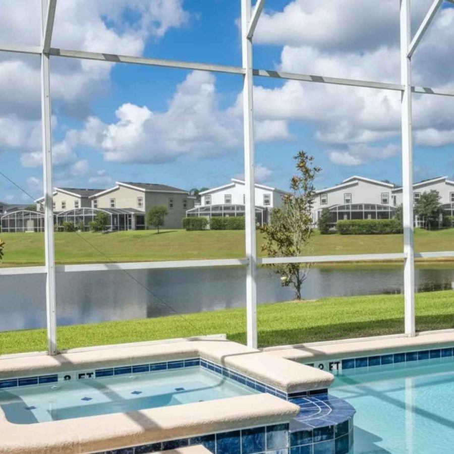 Piscina y spa con mosquitero frente al lago en una propiedad de lujo en Florida.