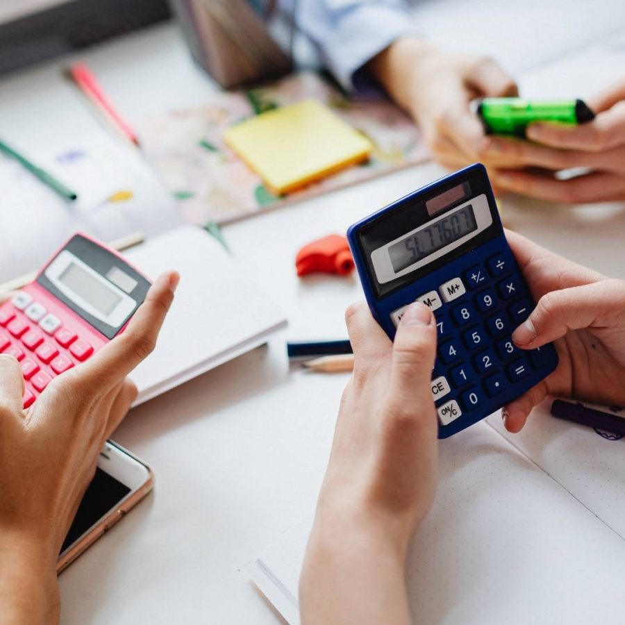 Varias personas utilizando calculadoras y smartphones en una mesa con notas para calcular la rentabilidad real de una casa vacacional.