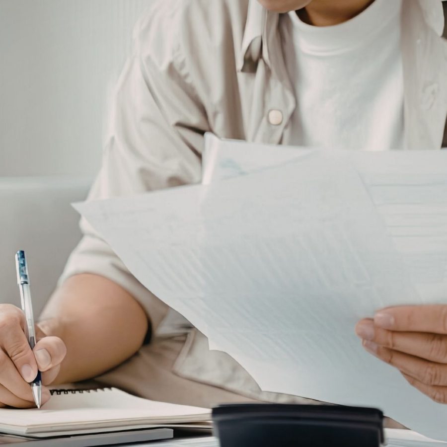 Persona revisando contratos y documentos financieros para la gestión de inversiones inmobiliarias mediante una sociedad de responsabilidad limitada.