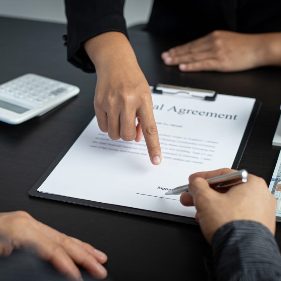 Un agente inmobiliario firma un contrato con un cliente en una oficina.