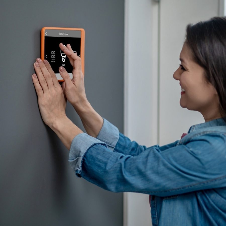 Mujer controlando sistema de domótica en vivienda inteligente, tecnología aplicada a casas de inversión inmobiliaria.