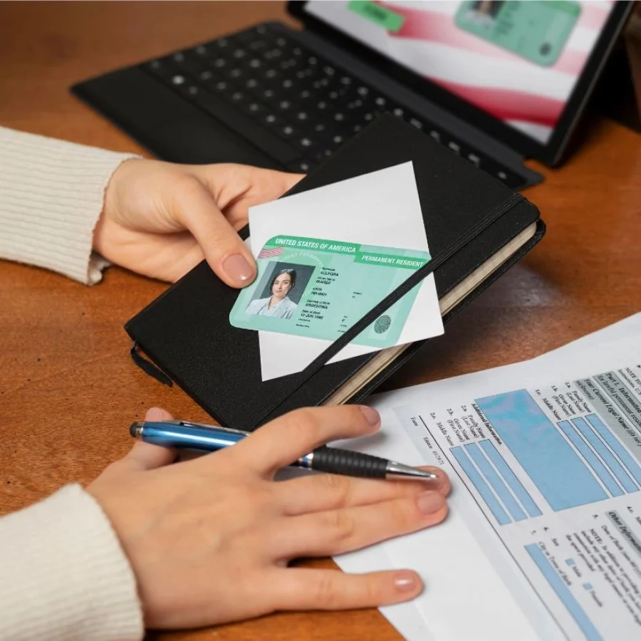 Manos sosteniendo una Green Card junto a formularios legales, representando los requisitos para renta corta en Orlando 2026.